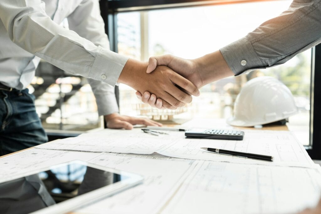 Architect and engineer construction workers shaking hands while working for teamwork and cooperation